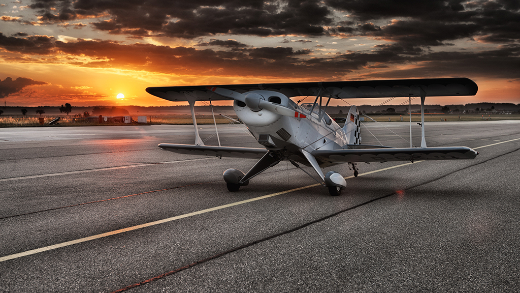 Avião Preto E Branco Com Pormenores Vermelhos Numa Pista De Alcatrão Durante Um Pôr-Do-Sol Nublado